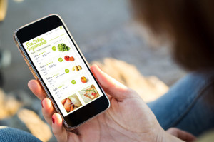 woman sitting in the street shopping groceries with her smartpho