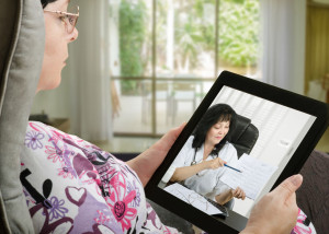 Woman communicates with telemedicine doctor by digital tablet