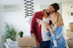 Young couple unpacking cardboard boxes at new home moving in concept