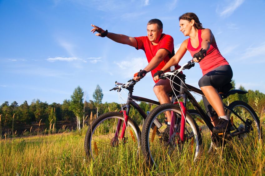 19773185 - couple of cyclists riding bicycles in meadow