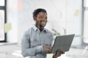 businessman with laptop at office glass board