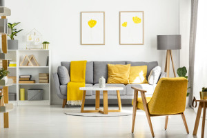 Yellow wooden armchair and table in living room interior with po