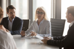 Serious middle aged businesswoman talks at group board executive meeting