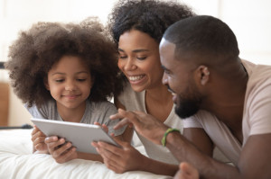 Happy black family using digital tablet together.