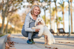 Elderly woman walking with a dog outdoors.