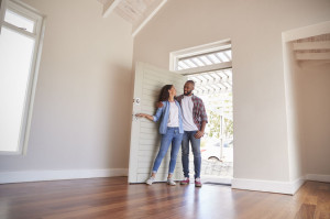 Couple Opening Door And Walking In Empty Lounge Of New Home