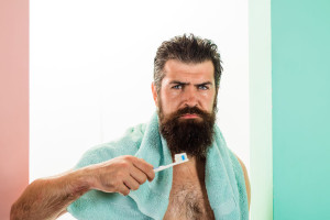 Serious bearded man brushing teeth. Oral care. Tooth brush. Tooth paste. Cleaning teeth. Morning treatments. Morning routine. Health care. Dental hygiene. Whitening teeth. Isolated.