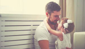 happy family child baby girl in arms of his father at home