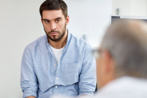 young male patient talking to doctor at hospital