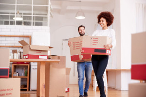 Smiling Couple Carrying Boxes Into New Home On Moving Day