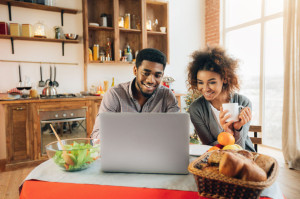 Happy african-american couple using laptop at kitchen