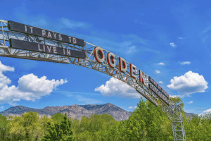 The welcome arch in Ogden Utah against vibrant trees and towering mountain
