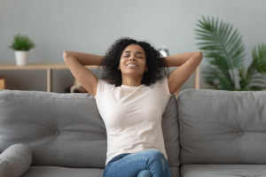 Serene african woman leaned on couch resting at home