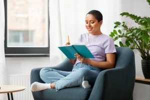 happy african american woman with diary at home