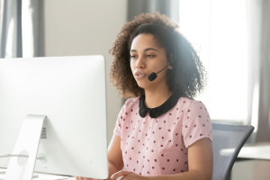 African call center operator in wireless headset talking using computer