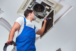 Worker repairing ceiling air conditioning unit