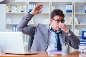 Businessman sweating excessively smelling bad in office at workp