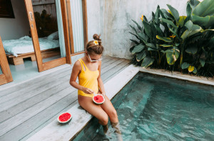 Girl eating watermelon in pool on luxury villa in Bali