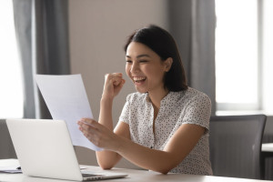 Happy asian businesswoman celebrate success looking at financial report