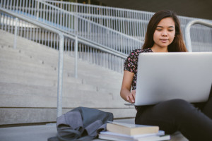 Young Asian university student using a laptop on campus