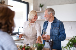 Group of senior friends at dinner party at home, cooking.