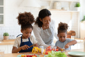 Loving biracial mom teach little kids cooking in kitchen