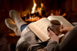 Woman reads book near fireplace