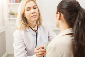 Doctor with stethoscope checking patient heart beat