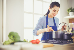 Cooking woman in kitchen with wooden spoon