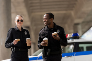 smiling police officers having coffee break with doughnuts