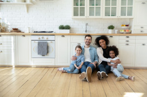 Portrait of multiracial family with kids on kitchen floor