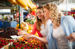 Young happy women shopping vegetables and fruits on the market