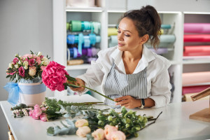 Enthusiastic female florist making a bouquet of pretty flowers