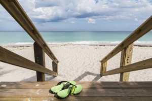 Wooden stairs on deserted beach duneswith green shoes