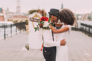 Happy black wedding couple softly hugging on the rooftop during the wedding ceremony