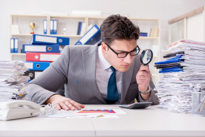 Male businessman with magnifying glass in office