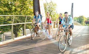 Happy millenial friends having fun riding bike at city park - Fr