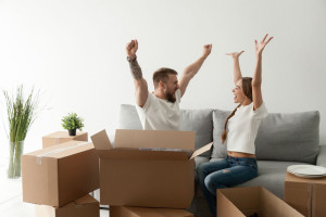 Happy excited couple sitting together on couch celebrating movin