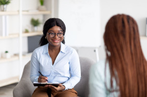 Happy black female counselor talking to female client on session at office, giving advice to patient