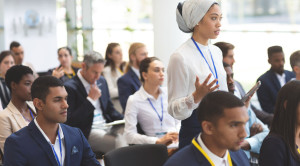 Side view of young mixed race businesswoman asking question during seminar in office building