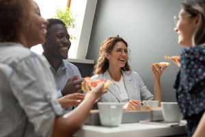 Multiracial company members having lunch eating pizza during break