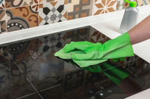 Cleaning a modern black ceramic hob by a microfiber