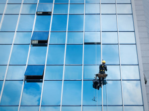 Window cleaner working on a glass facade suspended