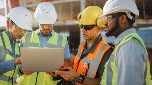 Diverse Team of Specialists Use Laptop Computer on Construction Site. Real Estate Building Project with Civil Engineer, Architectural Investor, Businesswoman and Worker Discussing Blueprint Plan
