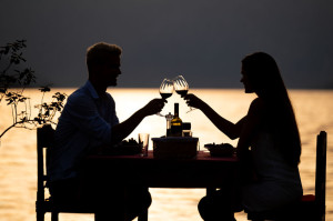People, vacation, love and romance concept. Young couple enjoying a romantic dinner on beach.