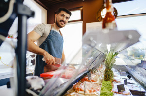 Portrait of confident young salesman standing in butcher's shop