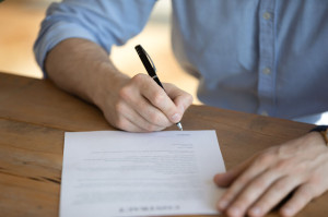 Hired employee signing employment contract, close up image