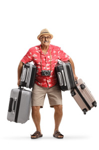 Full length portrait of a mature man holding heavy suitcases
