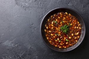 Bean soup in a black bowl. Dark background. Copy space. Top view.