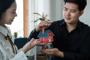 Asian couple are using their hands to protect The concept of the use of gestures in real estate investors, leasing insurance, purchase and sales contracts and maintenance